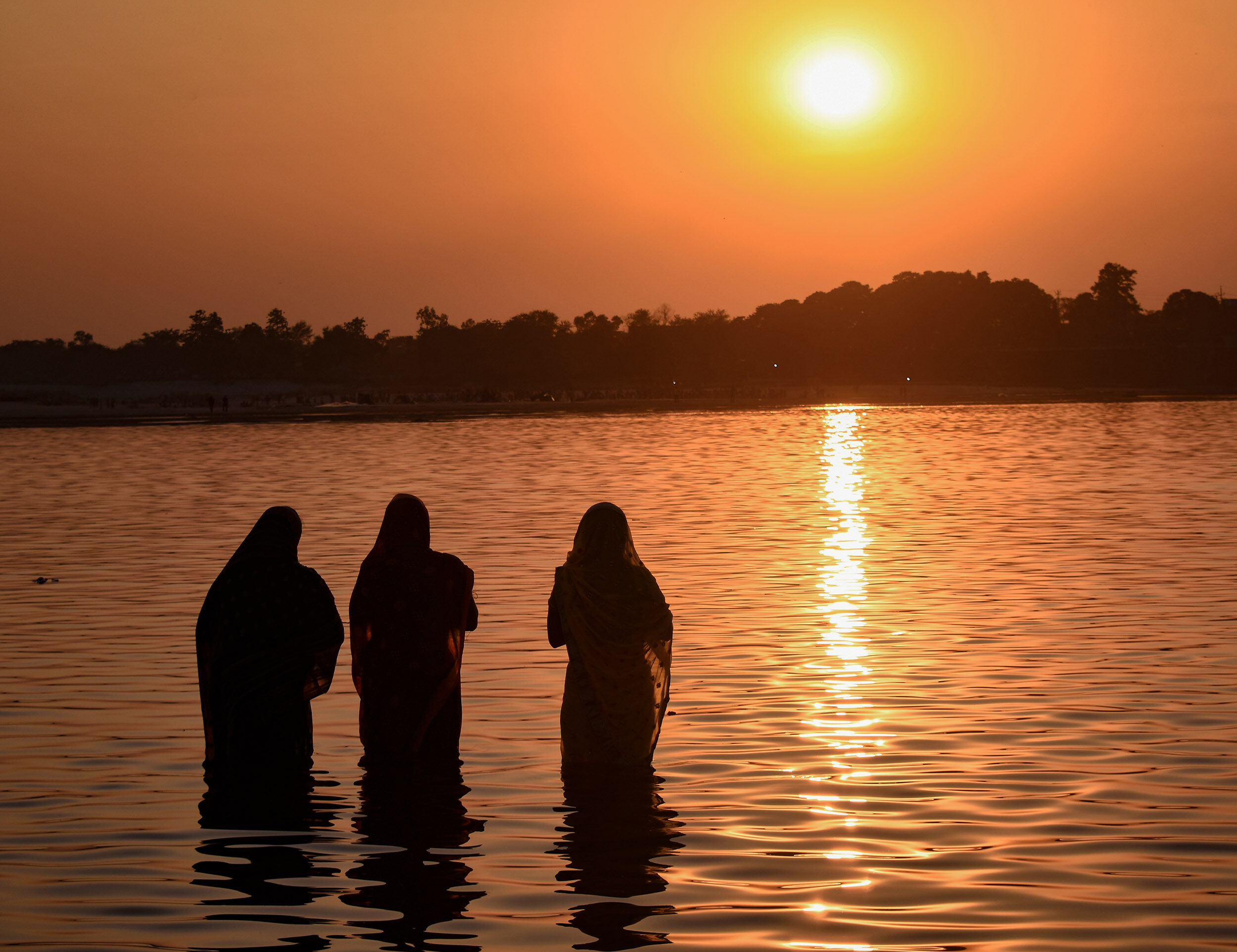devotees making the traditional *arghya* offering to the setting or rising sun, a central Chhath Puja ritual.